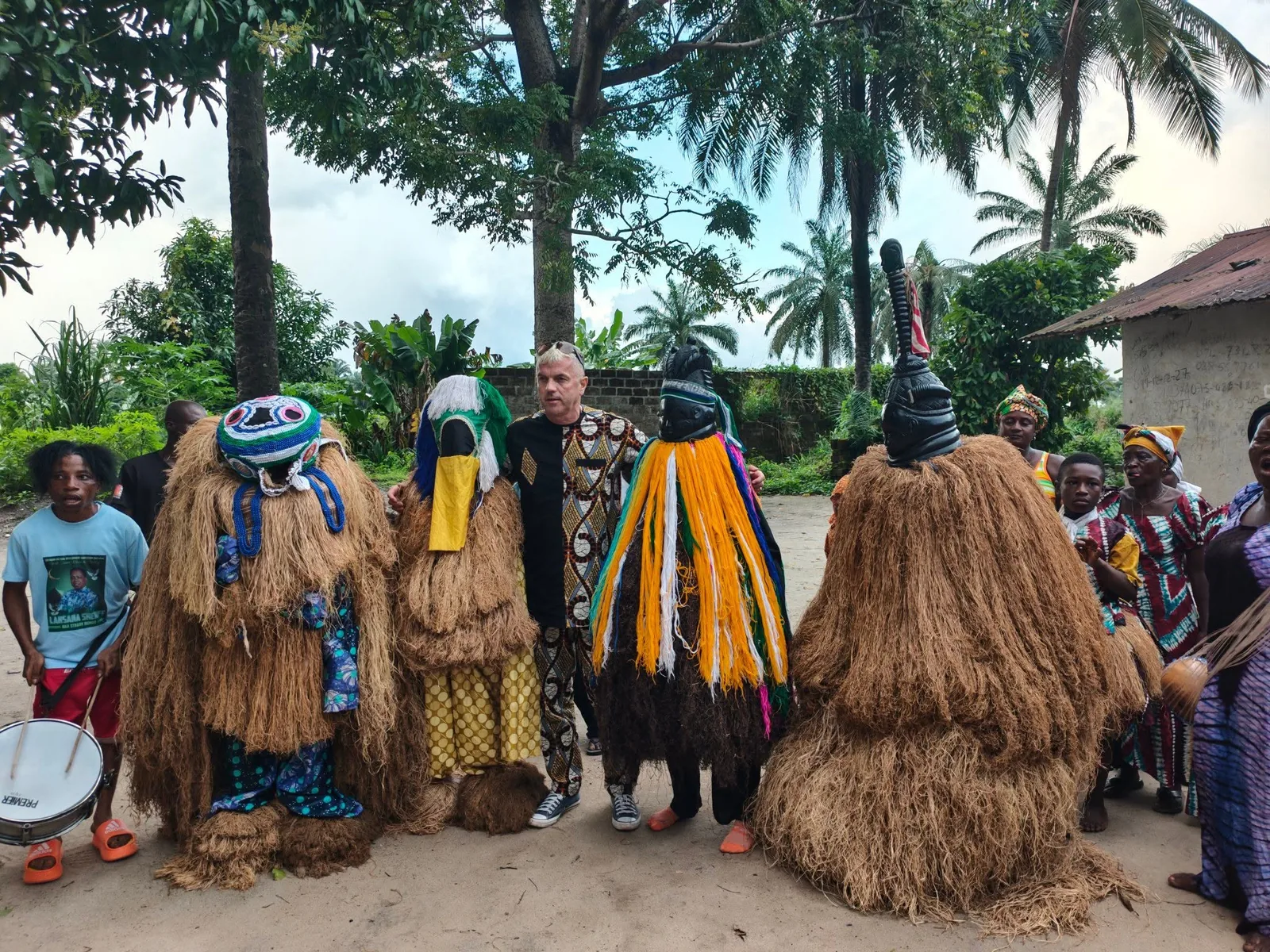 Raffia masked dancers performing alongside a traveller