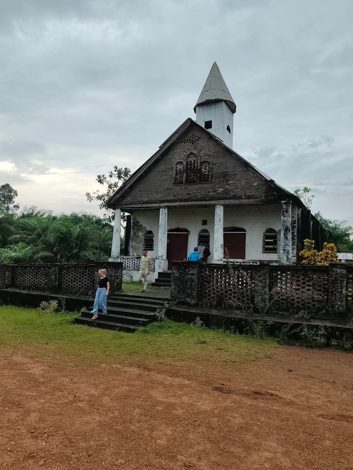 Traveller outside a weathered colonial-era church in West Africa