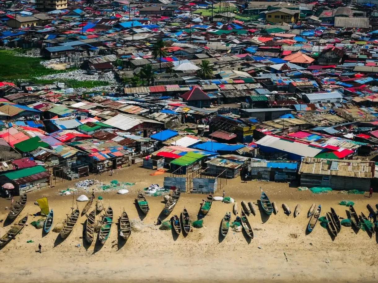 Aerial view of a West African fishing village with pirogues on the shore