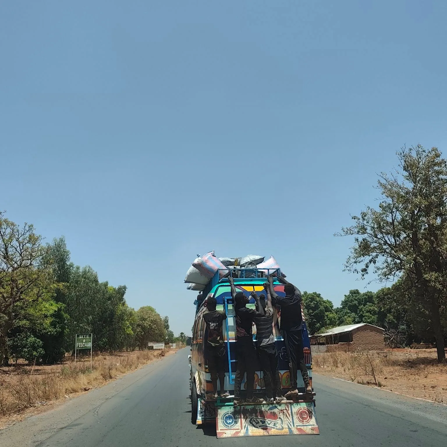 Loaded bush taxi carrying passengers and cargo on an open West African road