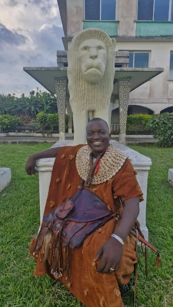 Guide in traditional dress seated before a lion monument