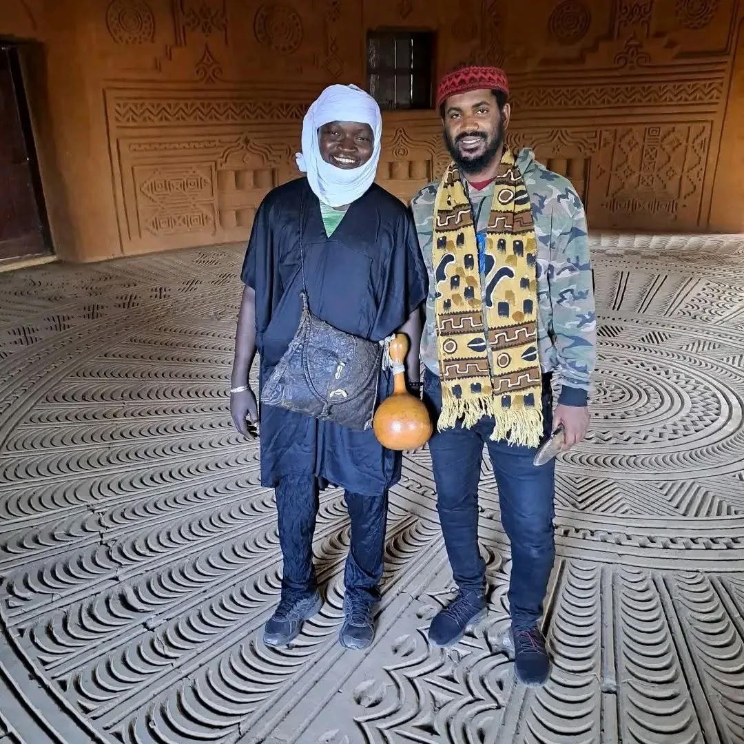 Travellers inside a room with intricate Malian mud-relief decoration