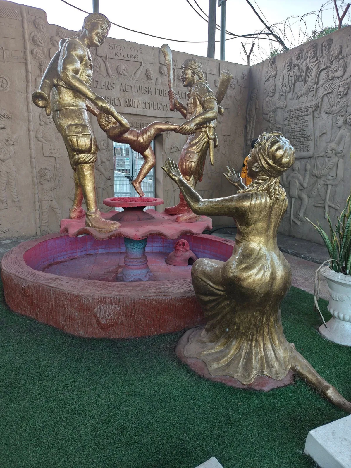 Golden sculpted figures around a public memorial fountain