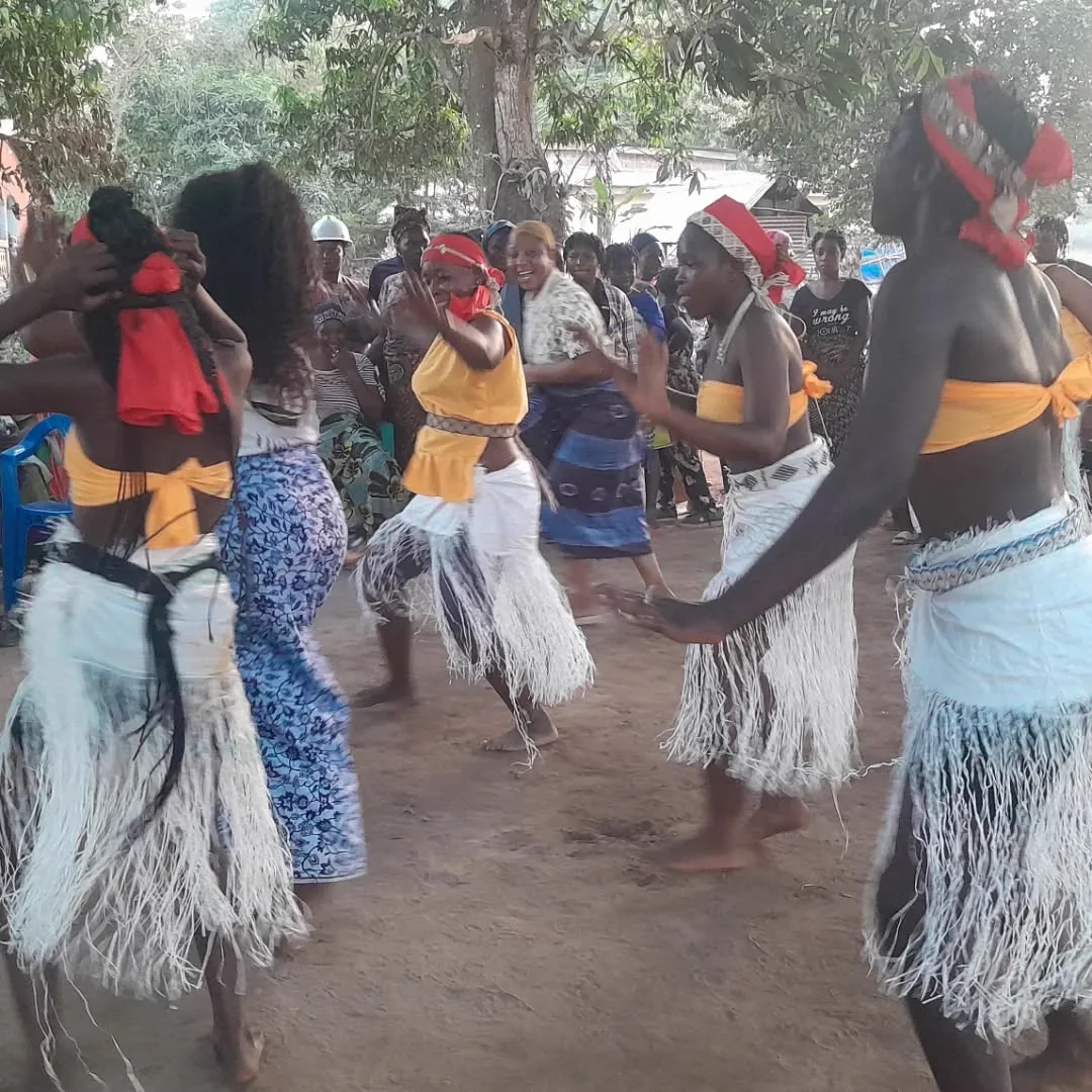 Traditional dancers in raffia skirts performing in a Guinea village
