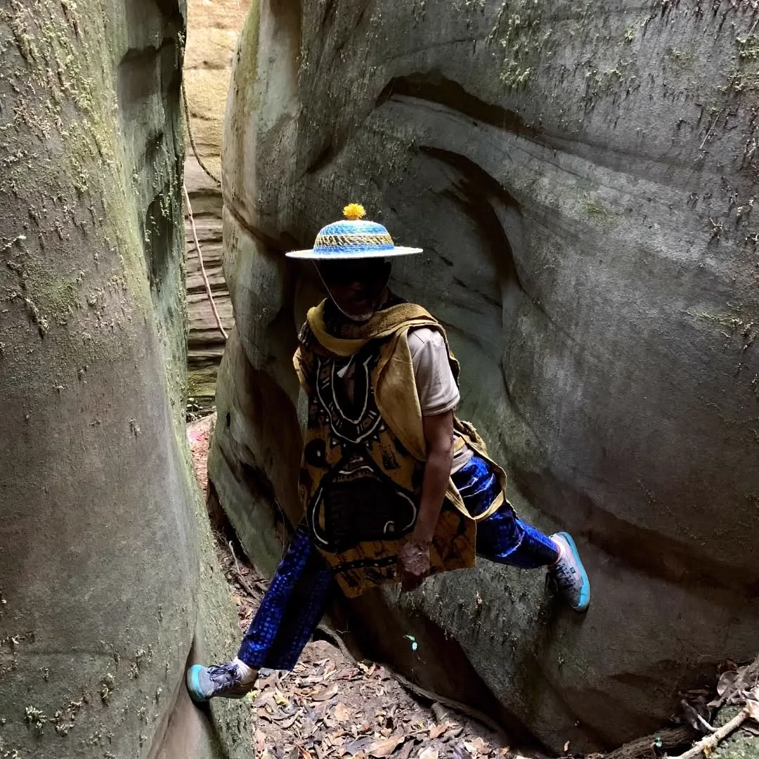 Traveller squeezed through a narrow sandstone slot canyon in Guinea