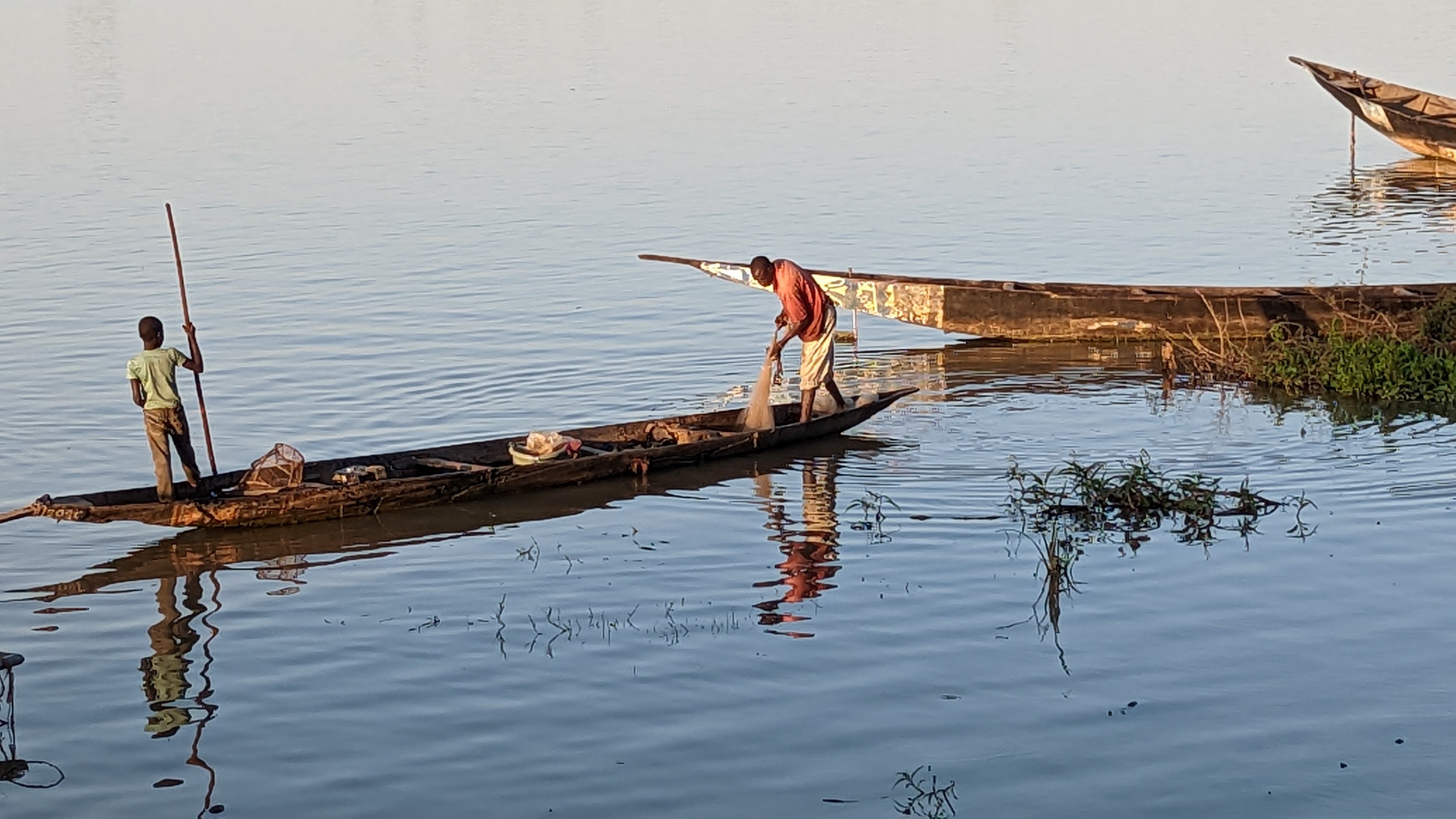 Fishermen in wooden pirogues on the still Niger River at dawn